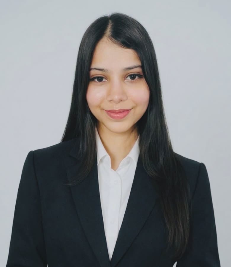 Nishita Singh, with long dark hair, in a black blazer and white shirt, against a light background.