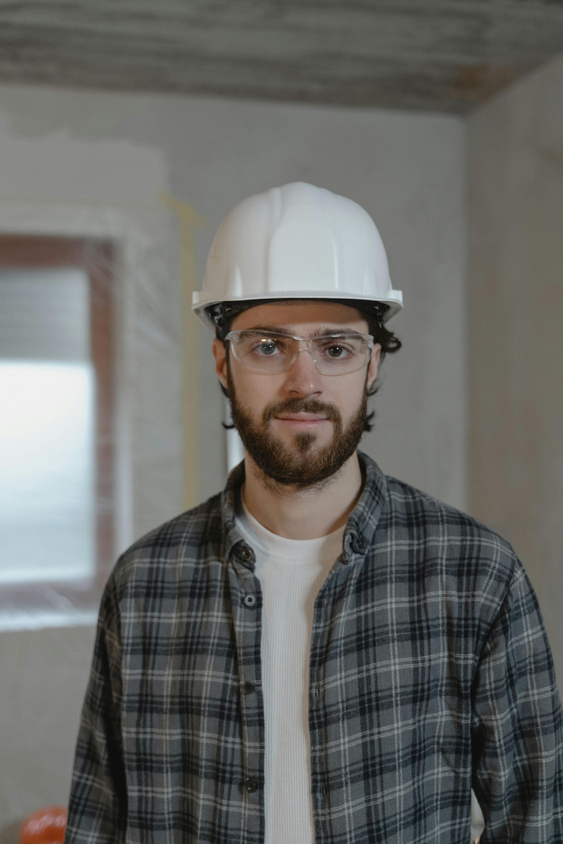 A contractor in a hard hat and safety glasses on a job site.